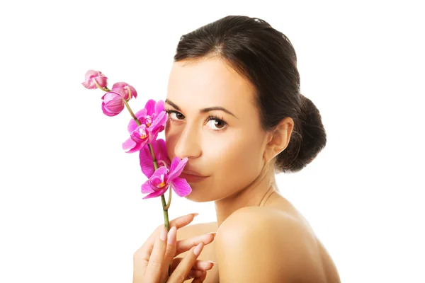 Nackte Frau mit lila Orchidee, die in die Kamera schaut — Stockfoto