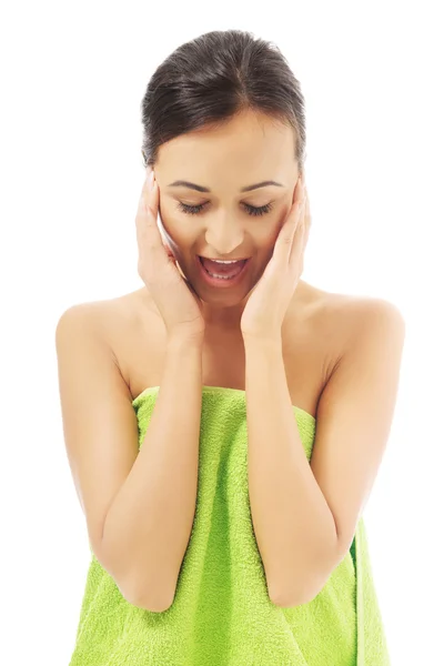 Překvapen žena zabalená v ručníku dotýká její obličej — Stock fotografie