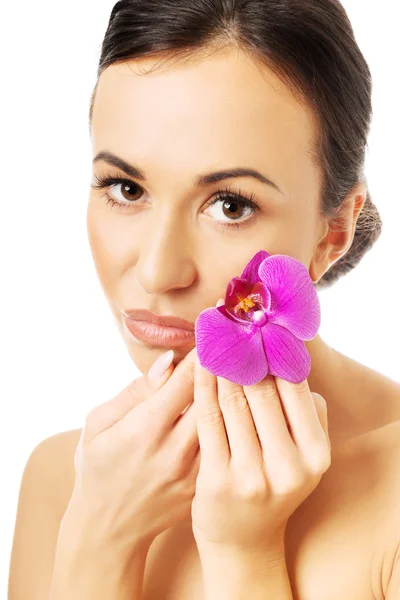 Donna nuda con petalo di orchidea viola vicino al viso — Foto Stock