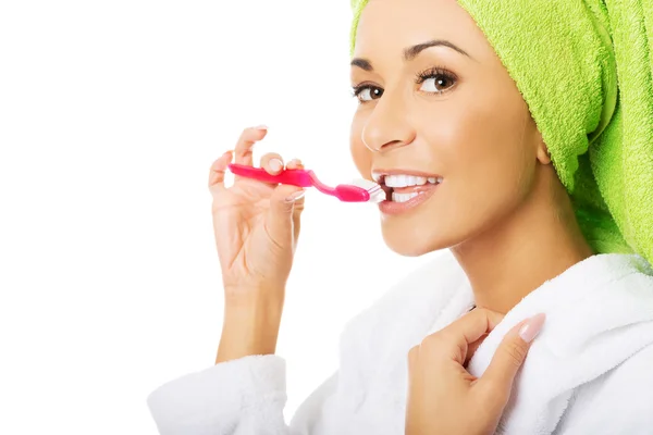 Retrato de una mujer en albornoz cepillándose los dientes — Foto de Stock