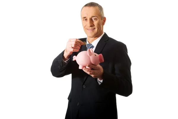Affärsman att sätta ett mynt för piggybank — Stockfoto