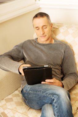 Evde dijital tablet kullanan olgun bir adam