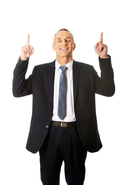 Businessman pointing upwards and smiling at camera — Stock Photo, Image