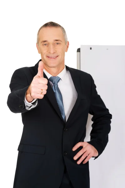 Male executive with ok sign near flip chart — Stock Photo, Image