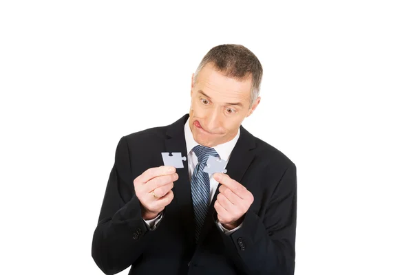 Businessman trying to connect puzzle pieces. — Stock Photo, Image