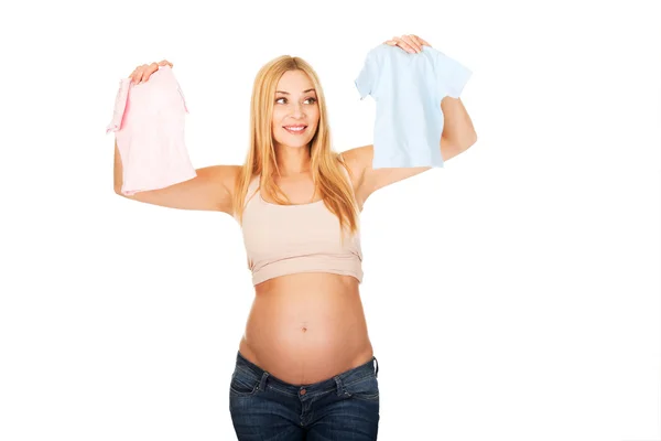Mulher grávida com duas camisas pequenas do bebê — Fotografia de Stock