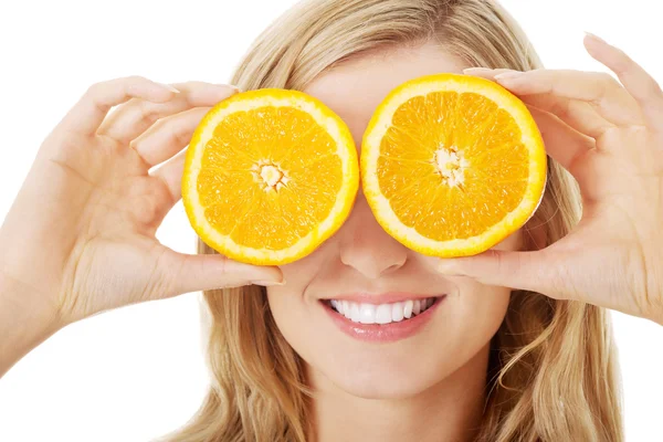 Młoda kobieta trzymając pomarańcze na oczy — Zdjęcie stockowe
