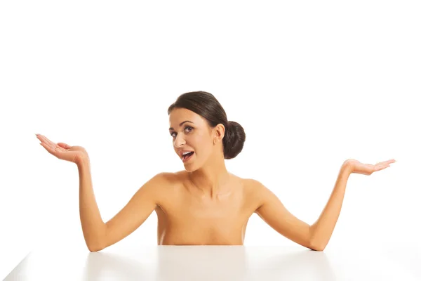 Nude woman sitting, making undecided gesture — Stock Photo, Image