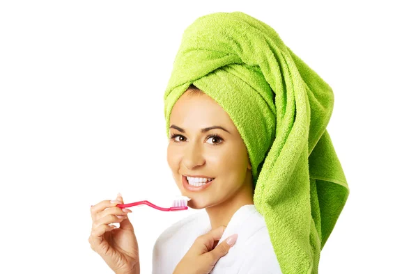 Portrait of a woman in bathrobe brushing teeth — Stock Photo, Image
