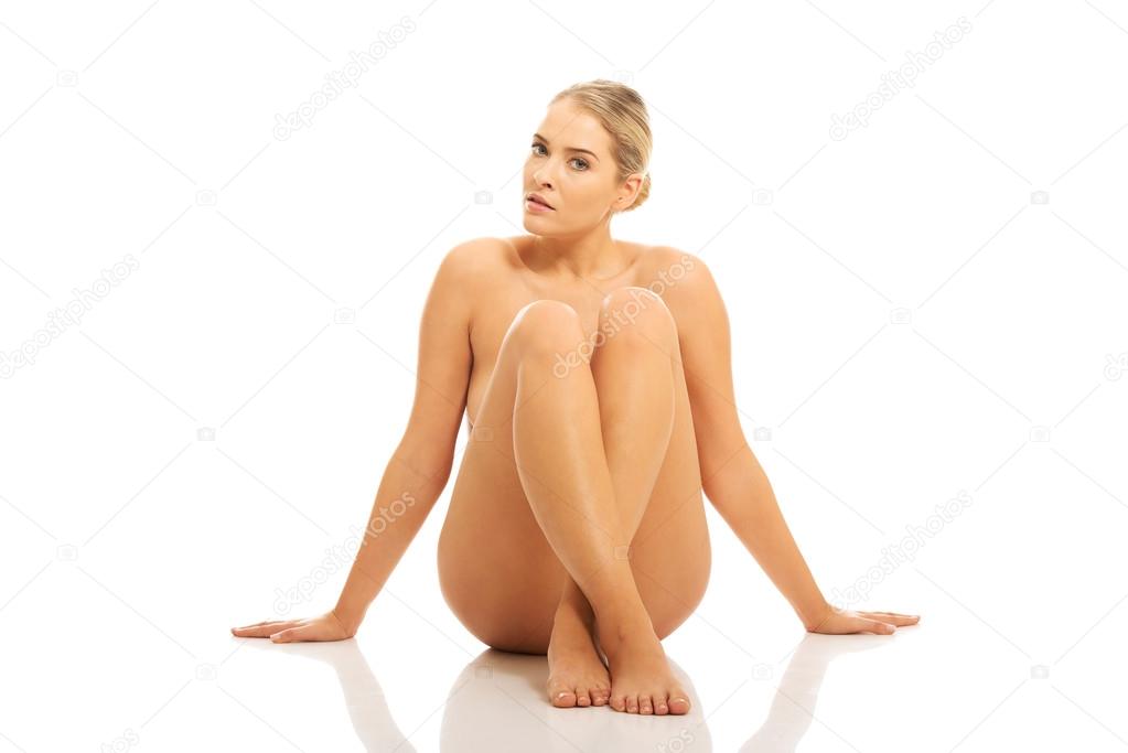 Nude woman sitting on the floor buttres her hands