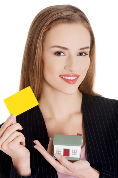 Empresaria sosteniendo modelo de casa y tarjeta amarilla — Foto de Stock