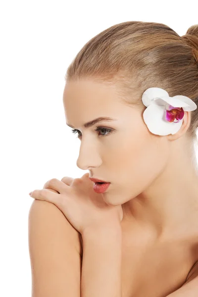 Retrato de mujer desnuda con flor de orquídea en la oreja — Foto de Stock