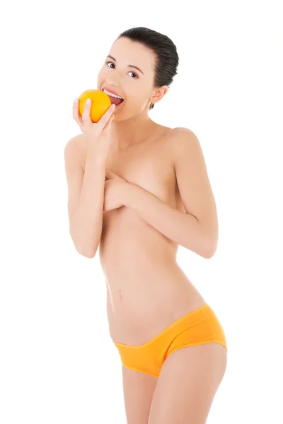 Mulher de cueca comendo uma laranja — Fotografia de Stock