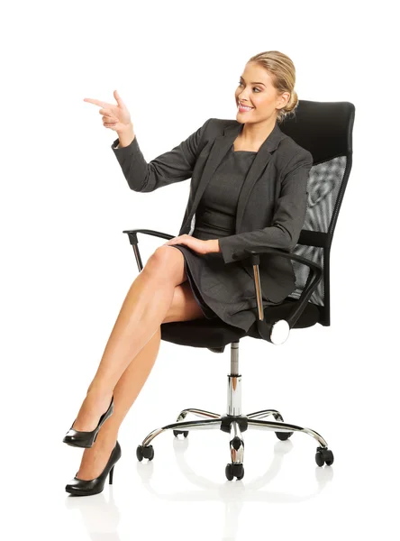 Businesswoman sitting on a chair and pointing — Stock Photo, Image