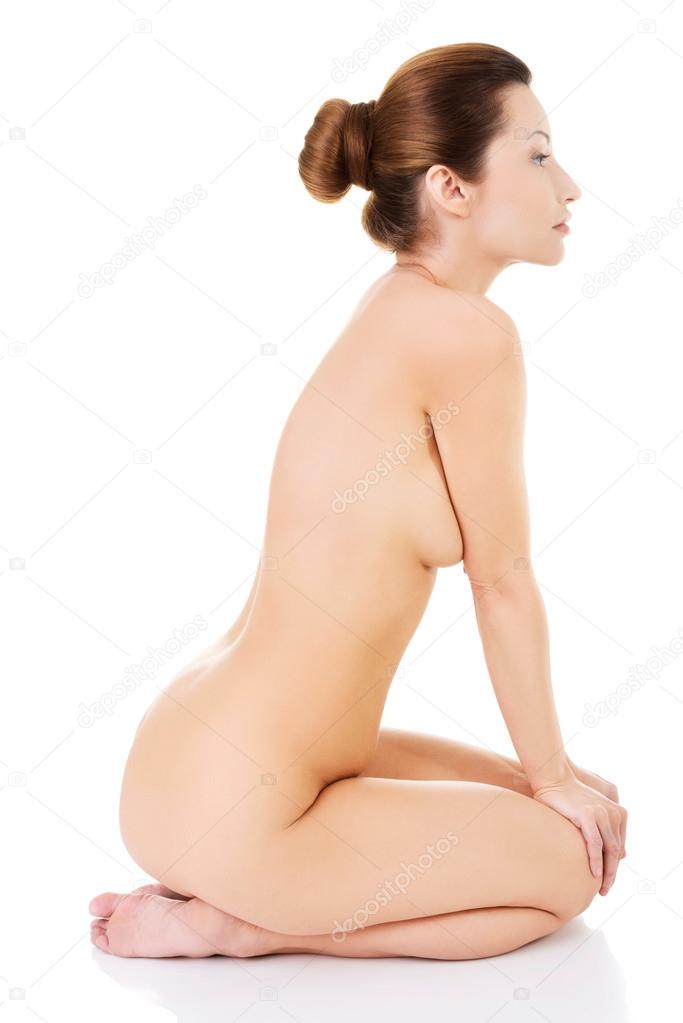 Side view of nude woman sitting on her knees