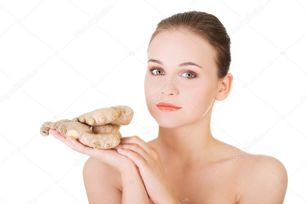 Portrait of nude woman holding raw ginger