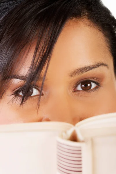 Joven mulato mujer escondiéndose detrás de un libro — Foto de Stock