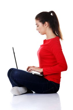 Yan görünümü kadın bağdaş kurup laptop ile oturuyordu