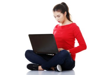 Dalgın kadın bağdaş kurup laptop ile oturuyordu
