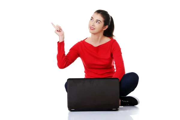 Woman sitting cross-legged pointing up — Stock Photo, Image