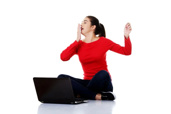 Trött kvinna sitter med korslagda ben med laptop — Stockfoto