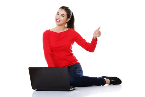 Woman sitting cross-legged with laptop pointing up — Stock Photo, Image