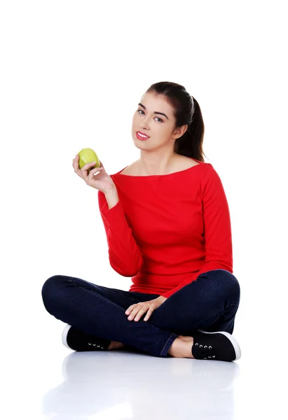 Femme assise jambes croisées tenant une pomme — Photo
