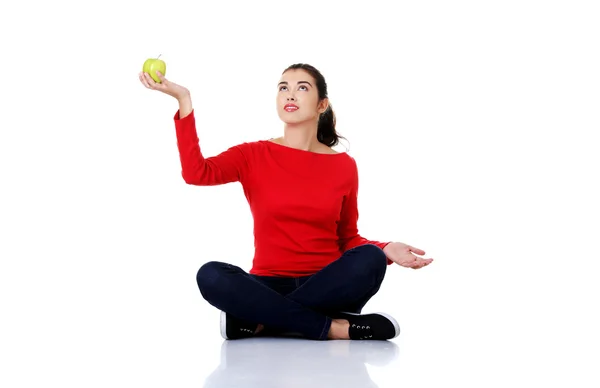 Woman sitting cross-legged holding an apple — Stock Photo, Image