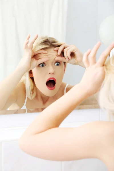 Mujer rubia joven preocupada revisando sus arrugas — Foto de Stock