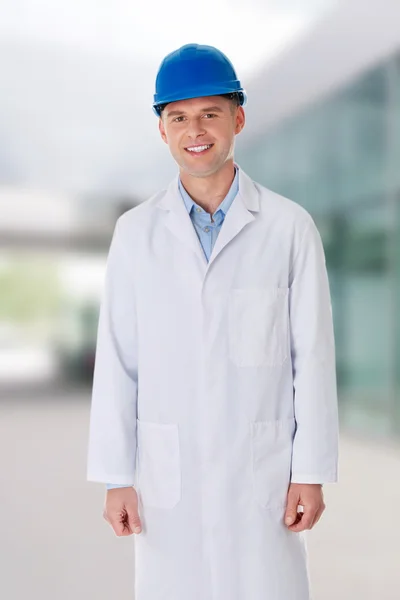 Hombre con una bata de laboratorio y casco —  Fotos de Stock