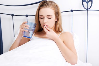 Yatakta hap alan bir kadın