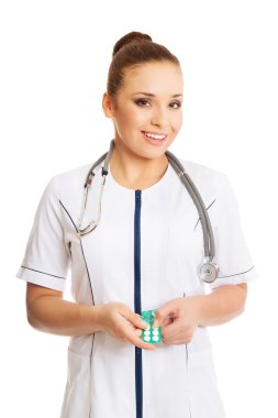 Kadın doktor hapları tutuyor.