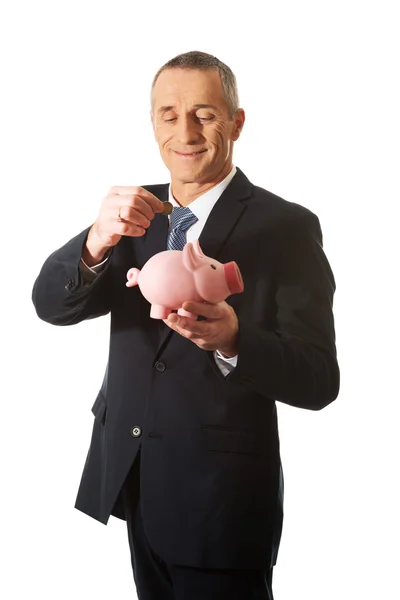 Affärsman att sätta ett mynt för piggybank — Stockfoto