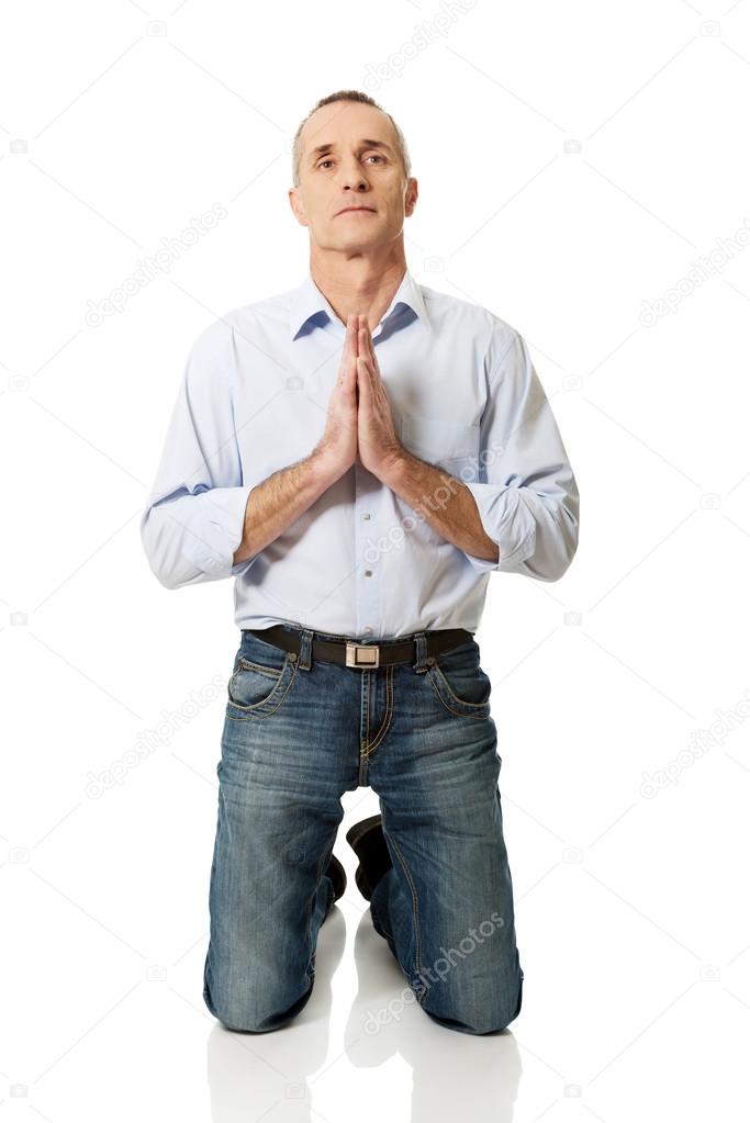 Mature man praying to God on knees