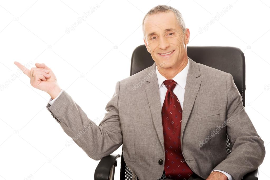 Businessman sitting on armchair and pointing