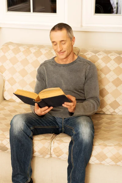 Mature man reading a book at home — Stock Photo, Image