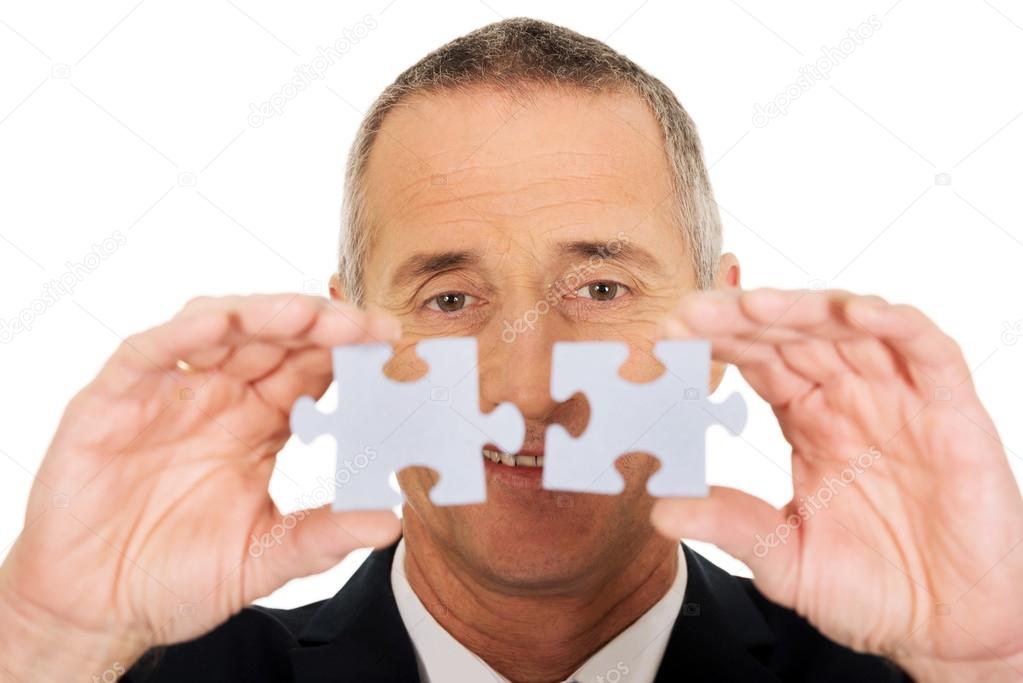 Businessman trying to connect puzzle pieces.
