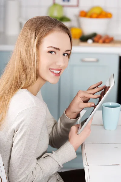 Ung kvinna som använder en surfplatta dator hemma — Stockfoto