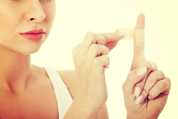 Frau klebt Klebeband auf ihren Finger. — Stockfoto