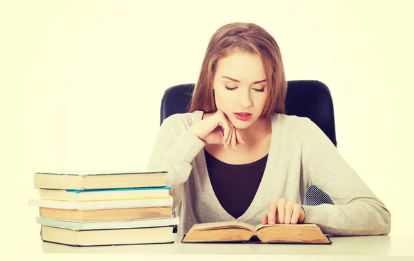 Casual student vrouw zitten door stapel boeken. — Stockfoto