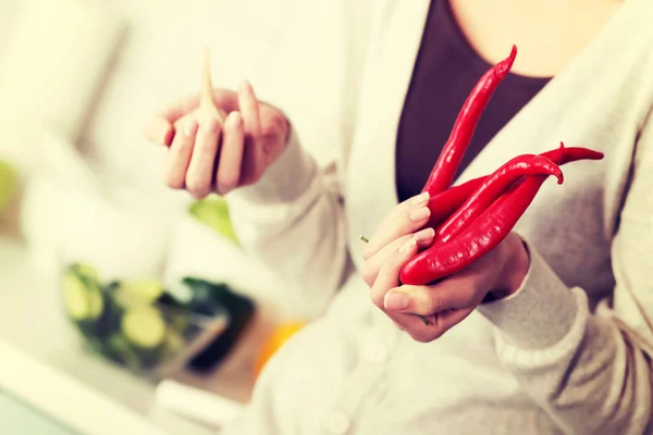 Woman is holding chili peppers and garlic. — Stock Photo, Image