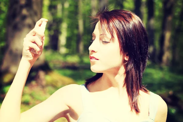 Mooie jonge vrouw in top met behulp van spray. — Stockfoto