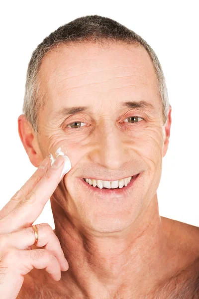 Man die crème op zijn gezicht aanbrengt — Stockfoto