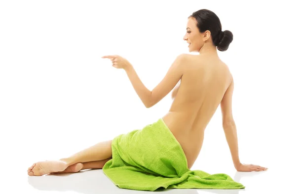 Женщина, завернутая в полотенце, указывая влево — стоковое фото