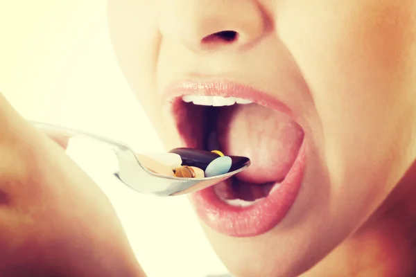 Young woman eating pills on a spoon. — Stock Photo, Image