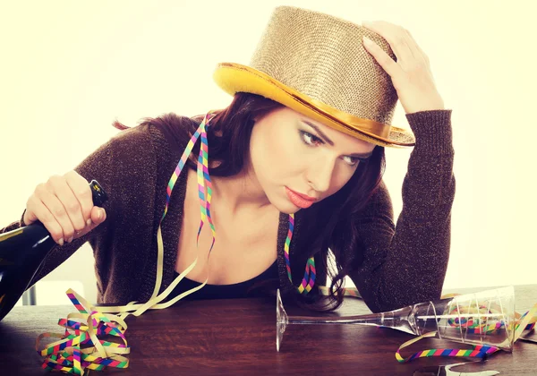 Mujer borracha junto a una mesa con una botella vacía . — Foto de Stock