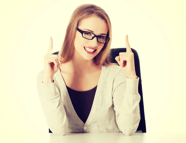 Beautiful casual woman sitting and pointing up — Stock Photo, Image