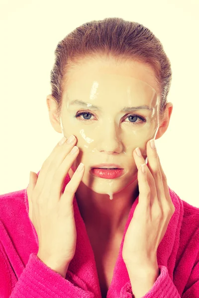 Mujer en albornoz rosa con máscara facial . — Foto de Stock