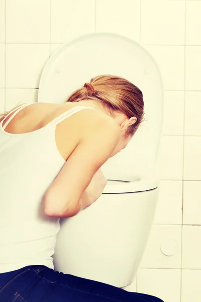 Mujer joven caucásica está vomitando en el baño . —  Fotos de Stock