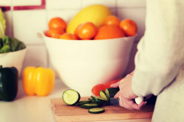 Vrouw snijden komkommer aan boord van de keuken. — Stockfoto
